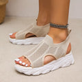 Beige open-knit slip-on sandals with side cutouts and chunky white soles, shown on feet