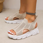 Beige open-knit slip-on sandals with side cutouts and chunky white soles, shown on feet