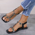 Black square-toe flat sandals with a clear strap lined with rhinestone butterflies and an elastic back strap