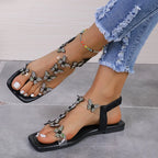 Black square-toe flat sandals with a clear strap lined with rhinestone butterflies and an elastic back strap