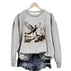 Gray Pheasant Print Crewneck Fleece Sweatshirt on a hanger over denim shorts
