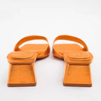 Pair of metallic orange square-toe mules with a wide strap and a low flared block heel on a white background