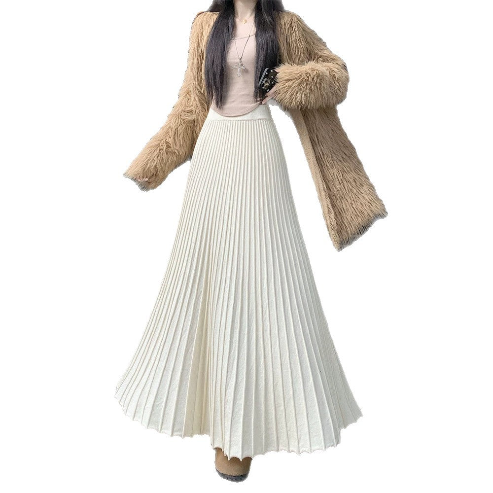 Woman wearing the Long Pleated Knit Skirt in off-white with a shaggy camel jacket